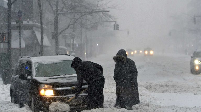 People work to free a stuck car during a snow storm on Saturday, Jan. 23, 2016. A snow emergency is currently in effect as accumulations in the city could top out at over a foot before the storm is expected to end later this evening.