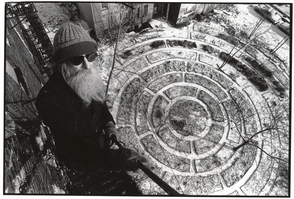 Adam Purple in winter 1982, when he was 52, on his building’s fire escape overlooking his huge Garden of Eden. Purple lived at the bottom of the abandoned building. Four years later, the city bulldozed his garden to make way for public housing. Photo by Harvey Wang