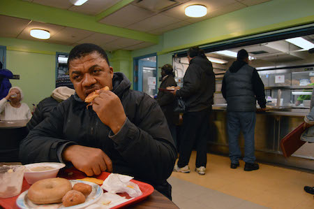 Finding Their Daily Bread 2 Inside from the freezing cold, Ezekiel takes a bite out of a ham sandwich at the New York Common Pantry. | JACKSON CHEN
