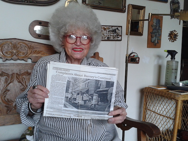 Barneys Back on Seventh, Bad Blood in Tow 2 In her Penn South apartment, Gloria Sukenick holds an Aug. 21, 1986 copy of the Chelsea Clinton News. Protest signs include the slogans “Barneys Construction Means Chelsea’s Destruction” and “Press Pants, Not Tenants.” Photo by Scott Stiffler.