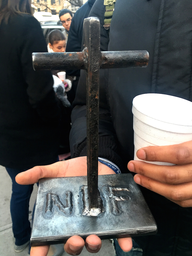 The first firefighter that went up the fire escape at 121 Second Ave. on March 26, 2015, later used part of the fire-escape ladder to make commemorative crosses for the families of both victims. A friend of Nicholas Figueroa’s held his cross, with the soldered initials “NF” and a candle cup for the vigil.  Photo by Patrick J. Eves 