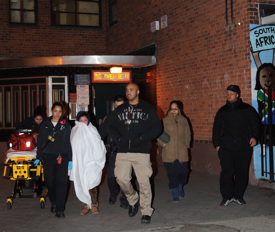 Police remove a domestic-violence victim from the Lillian Wald Houses on Fri., April 8. Responding officers shot a pit bull that attacked them during the incident.  Photo by C4P