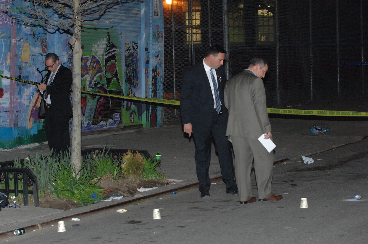 Detectives examined the scene in front of 635 E. 12th St. on Thurs., April 14, after Elliot Caldwell was fatally shot. White cups indicate where numerous spent bullet casings were located.  Photo by C4P