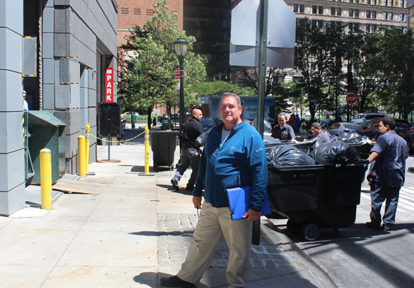 Photo by Bill Egbert Bruno Pomponio, center, the director of parks operations for the Battery Park City Authority, supervises the daily ritual of workers from the surrounding residential buildings lining up to load the day’s trash to the compactor on Second Pl., the green device on the left. When the dumpster is full, the city sends a truck to pick it up.