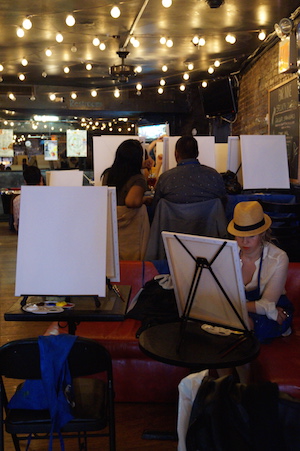 Attendees to Bar Nine's Painting Circle event sit down by their blank canvasses and start sipping their drinks. Photo by Nicole Javorsky.