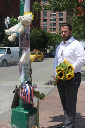Photo by Colin Mixson Travis Maclean stands beside the memorial to his wife Olga Cook on a light pole on the Hudson River Greenway near where she was struck and killed by hit-and-run driver while she cycled across the greenway’s notorious intersection with Chambers St. on June 11.