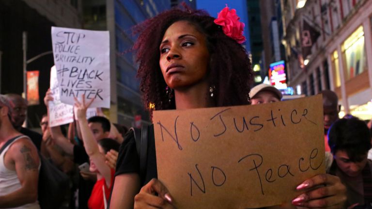 A sign states the cause as demonstrators march through Manhattan on July 7, 2016, to protest the deaths of two black men at the hands of police in Louisiana and Minnesota. 