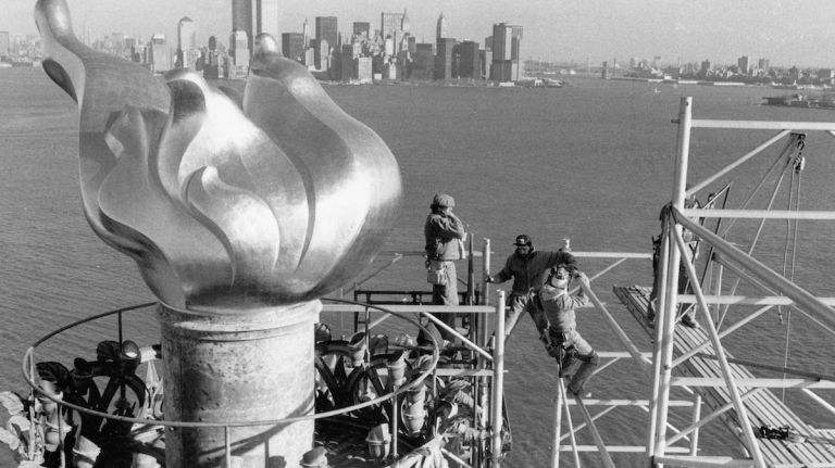 The New York City skyline is seen in the background as workers remove scaffolding from around the torch of the Statue of Liberty on Dec. 17, 1985.
