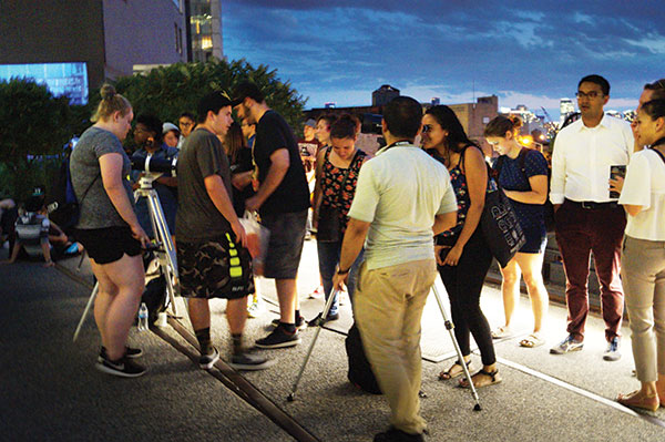 As the sky darkens, High Line visitors crowd around the telescopes for their turn at spotting the stars and the planets. Photo by Nicole Javorsky.