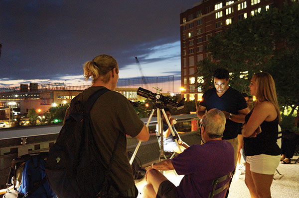 Carey Horwitz sits behind a telescope and answers the questions of people walking along the High Line. Photo by Nicole Javorsky.