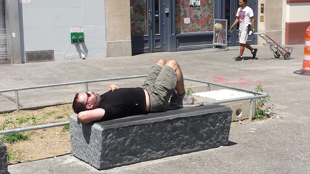 Lounging on a new bench of hewn stone in the Cooper Square part of the plaza project.