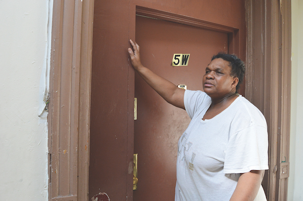 Sandra Johnson outside of her apartment, which still bears signs of plastic taped up on her doorframe p to keep out dust from renovations she believes her landlord is carrying out illegally in her building. | JACKSON CHEN 
