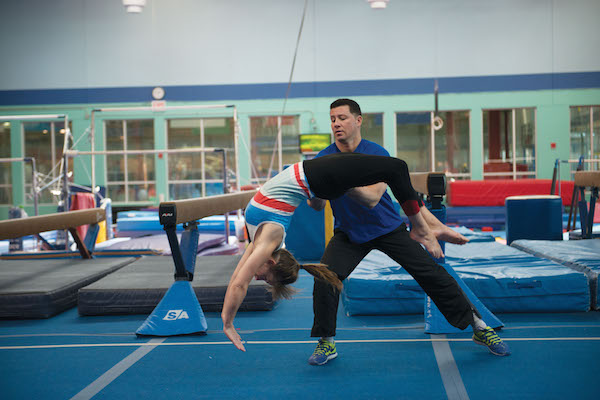 Chelsea Piers instructor Hector Salazar helps a student flip backwards. Photo by Scott McDermott. 