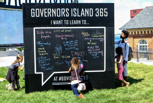 Photo by Tequila Minsky The city is inviting visitors to Governors Island to write their ideas about how to make the 150-acre park a better place to play, learn and work on a giant black cube at the Soissons Landing through Sept. 25.