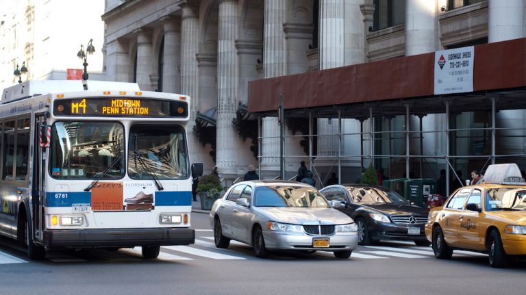 Bus, private cars and taxi sharing a New York City street.