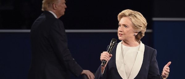 In background, per diem zombie extra Donald Trump grabs a chair while locking down the creepy sociopath vote. Photo via hillaryclinton.com.