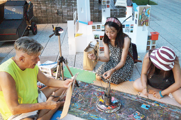 While Wen Chang's childhood friends work on their paintings, David Everitt-Carlson prepares more cardboard squares. Photo by Nicole Javorsky.