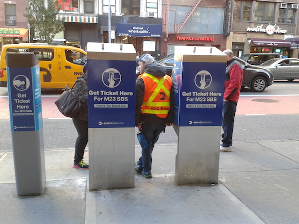Upgraded M23 Bus Still Riding A Learning Curve 5 The MTA has been stationing employees at each M23 SBS stop to show riders how to buy their SBS tickets before boarding, which the agency said is more efficient. Seen here, W. 23rd St. near Seventh Ave. Photo by Scott Stiffler.