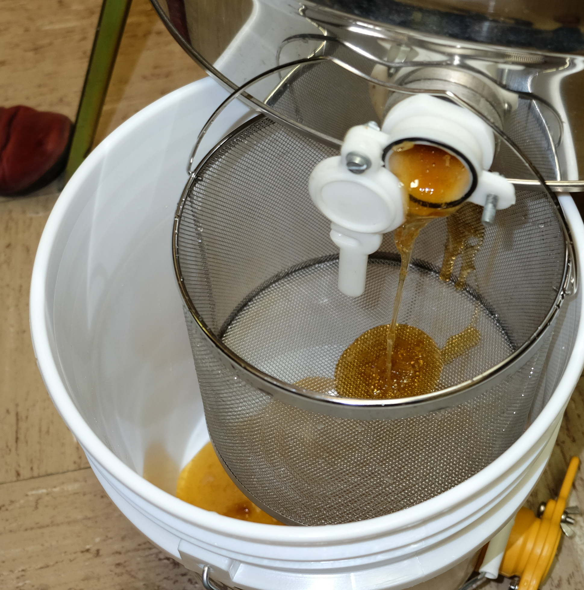 Honey flows from the extractor and any wax is filtered from the sieve.