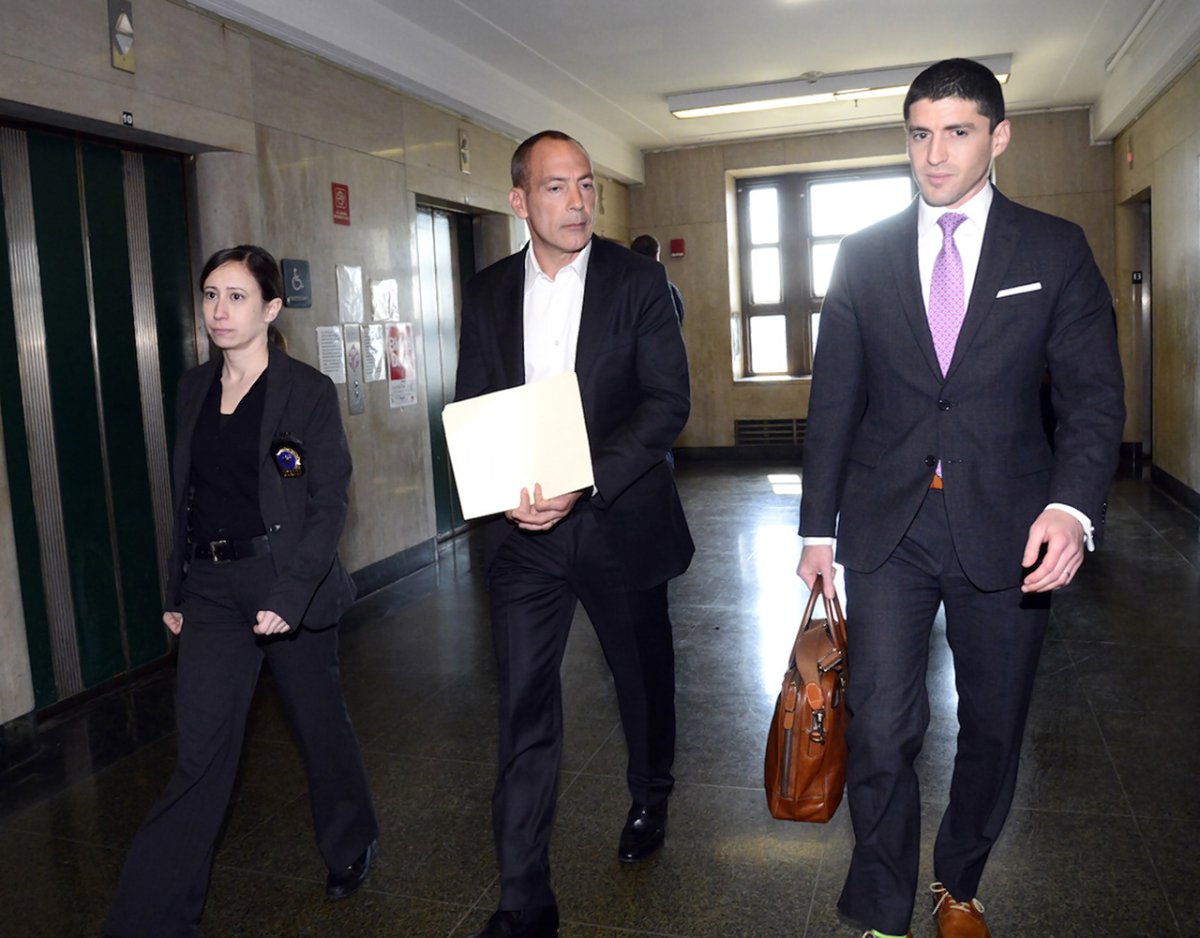 Landlord Steven Croman — holding a folder to cover his handcuffs — being walked into Manhattan Supreme Court this past May to be arraigned on a slew of charges filed against him by Attorney General Eric Schneiderman. A detective is at left and Croman’s attorney is at right.  Villager file photo by Jefferson Siegel
