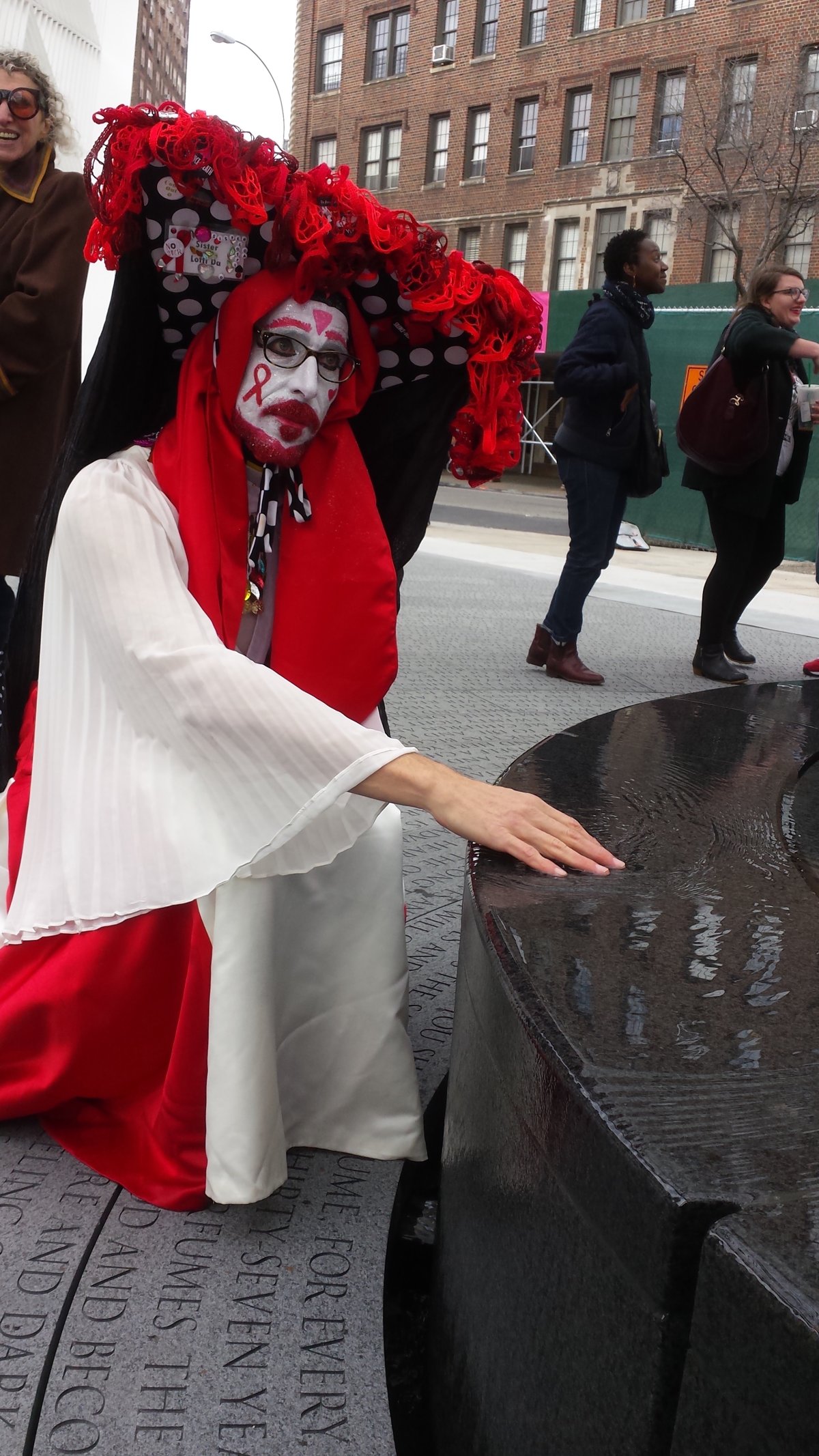 Sister Lotti Da of the Sisters of Perpetual Indulgence, from Windsor Terrace, Brooklyn, touched the water in the small circular fountain underneath the AIDS Memorial trellis at the dedication last week. One part of the memorial that is a little challenging is the ground treatment, which is a pastiche of phrases from Walt Whitman’s famous poem “Song of Myself.” Basically, the ground etching is so densely packed with phrases that it’s completely impossible to read — or even look at for long! But Lotti Da, looking on the bright side, said he was now inspired to go home and actually read the poem. So that’s something! Photo by Scoopy