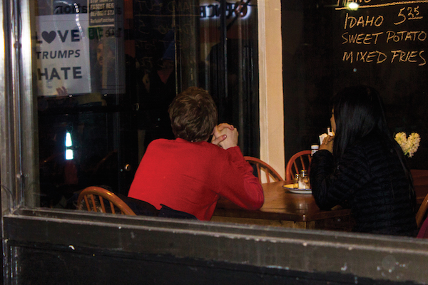 Activists Promise Grassroots Movement to Fight Trump 7 A woman and man watch as protesters pass a Downtown restaurant. Some marchers said that tolerance in daily life is one way to oppose a president who has a long record of disparaging women as well as ethnic and religious minorities. Photo by Zach Williams.