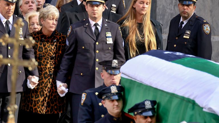 Patricia McDonald, wife of NYPD Det. Steven McDonald, follows her husband's flag-draped coffin out of St. Patrick's Cathedral following his funeral mass on Friday, Jan. 13, 2017. At her side, is her son Conor, right, a sergeant with the NYPD.