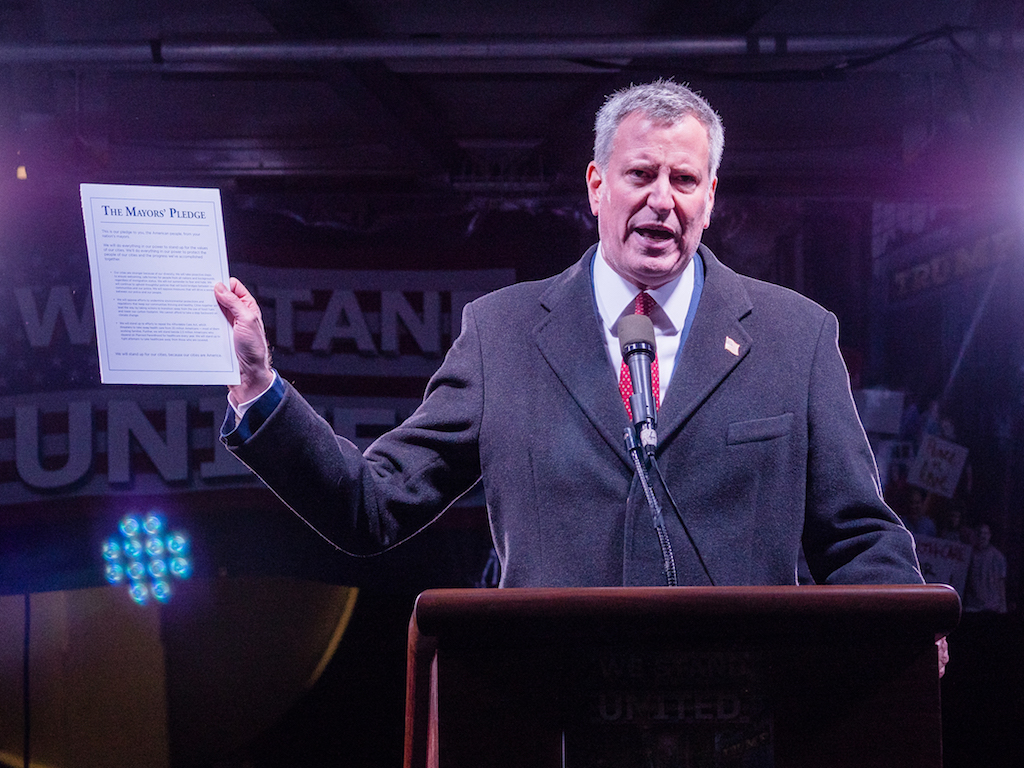 Mayor de Blasio held up a copy of the Mayors' Pledge, which contains a range of issues that he is vowing to advocate for — from defending immigrants to protecting the environment.
