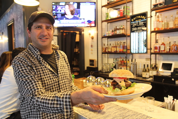 Burger Joint Puts Meat on the Bones of an Emerging Neighborhood 2 Larry Kramer shows off Whitmans’ flagship Juicy Lucy burger, a take on a Minnesota tradition of stuffing patties with cheese (the Whitmans version is stuffed with pimento). Photo by Dennis Lynch.