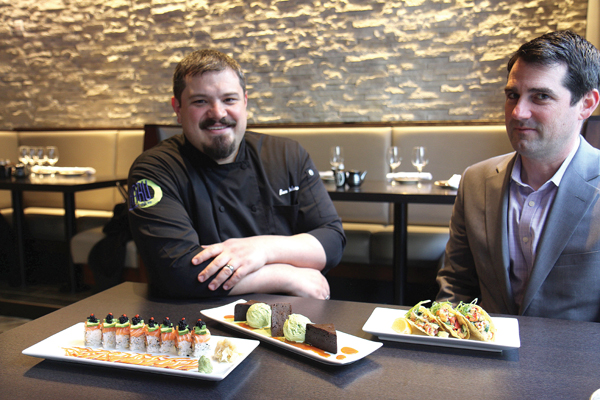 Executive Chef Ben Dodaro (left) and VP of Operations Seth Rose (right) show off a Hell’s Kitchen Roll, green tea ice cream with miso chocolate brownie, and their lobster tacos. Photo by Dennis Lynch.