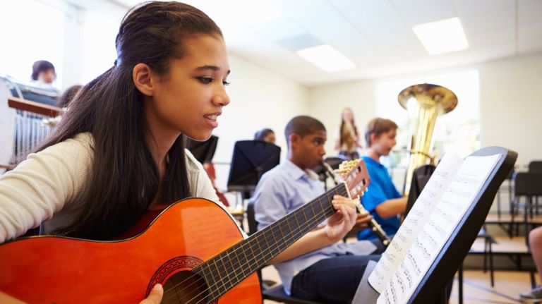 Low-income New York City neighborhoods benefit from arts and cultural programs, a new report says. Above, a student  plays guitar in high school orchestra.