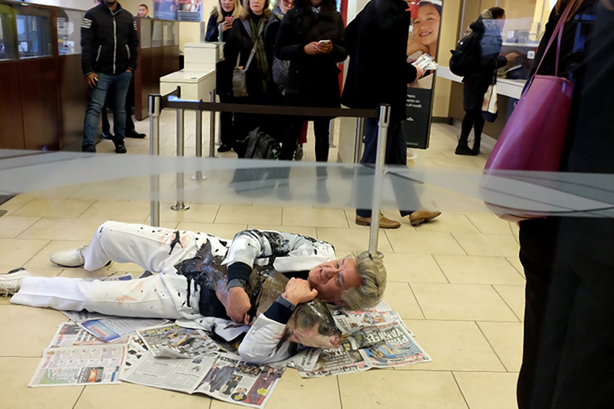 Reverend Billy wrestles with, to his surprise, a live carp after getting caught in an “oil spill” at a pipeline-promoting Wells Fargo bank branch at E. 34th St. and Madison Ave. on Feb. 15. Photo by John Quilty