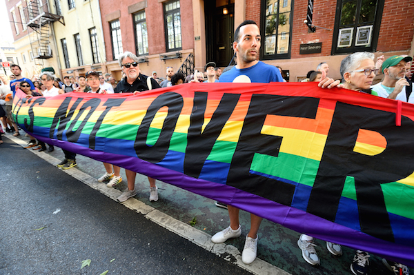 Rainbow Flag Creator Leaves Legacy of Pride 4 Gilbert Baker, at center in black shirt, holds up a banner at the vigil outside Stonewall the day after the Orlando massacre. Photo by Donna Aceto.