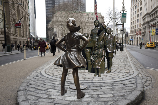 Original photo via Associated Press / Mark Lennihan – photo-illustration by Bill Egbert Placing a statue of refugee children at Bowling Green, with the “Fearless Girl” defiantly blocking they way, instantly transforms the girl-power icon into a symbol of anti-immigrant xenophobia — which some might reasonably argue infringes upon the State Street-sponsored  art instalation, and even violates the artistic intent sculptor Kristen Visbal.