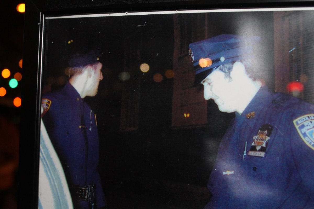 Protected from the rain by some plastic wrap, a framed photo of patrol partners Nicholas Pekearo, left, and Eugene Marshalik was left, along with a bouquet of flowers, on a lamppost on Bleecker St. last Thursday near where they were slain by a crazed gunman. Photos by Lincoln Anderson