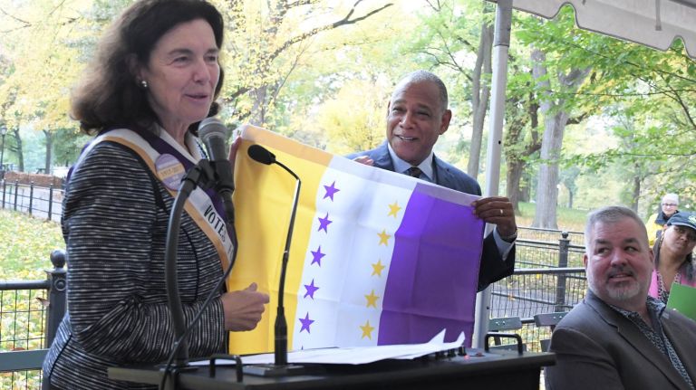 Coline Jenkins, great-great granddaughter of Elizabeth Cady Stanton, presents the 19th Amendment Suffrage Victory Flag to Parks Commissioner Mitchell Silver  as officials unveil the Central Park site for the 