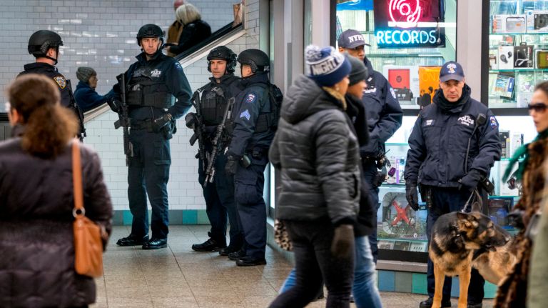 Heavily armed NYPD Emergency Services Unit officers and a K9 officer stand guard at Times Square subway station.
