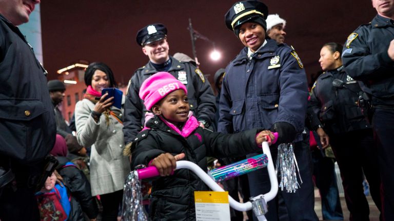 Veronika Victor, 5, of Brooklyn, sits on a new bike given to her by NYPD officers as part of the Brooklyn North 2nd Annual Sleigh Ride on Thursday, Dec. 21, 2017.