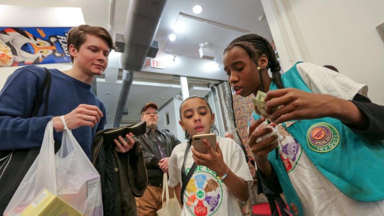 Brianna, 8, center, and Sanaa, 10, from Girl Scout Troop 6000 help Matthew Renne, from Brooklyn, with his cookie order during a sale in Union Square. 