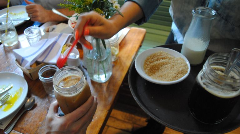 A server adds some CBD-infused sugar to a glass of iced coffee. 