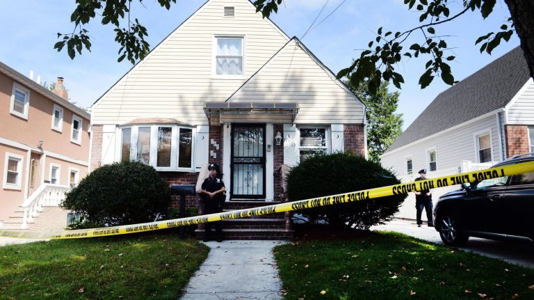 NYPD officers stand outside at a home on Ashby Avenue in Queens, where 1-year-old twins&nbsp;were found with severe trauma Wednesday night. One of the twins was later pronounced dead.