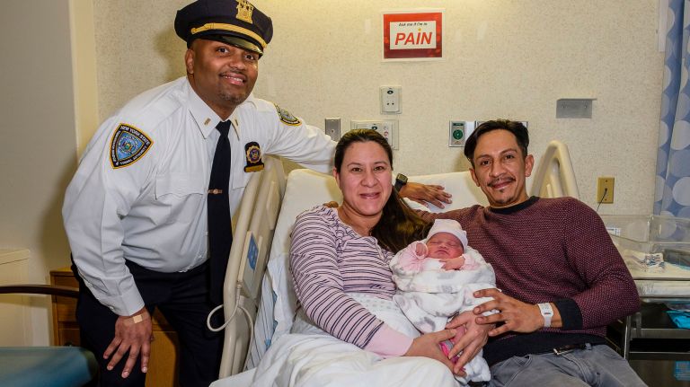 Newborn Alie Aurora snuggles between parents Maria and Ivan Albarracin in Bellevue hospital on Wednesday, joined by TBTA police Lt. Harry Persad who helped to deliver the baby at the Queens Midtown Tunnel.