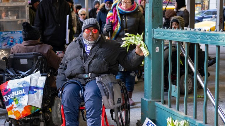 Dustin Jones of East Harlem, a board member of the Center for the Independence of the Disabled New York, joins other activists as they place flowers and signs Wednesday at the Seventh Avenue subway station, where Malaysia Goodson suffered a fatal fall down stairs Monday night.