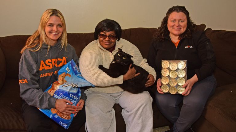 Antoinette Butler, center,&nbsp;is able to get more nutritious food for her feline friend Cujo now that the Food Bank for NYC provides pet food through a donation from the ASPCA.