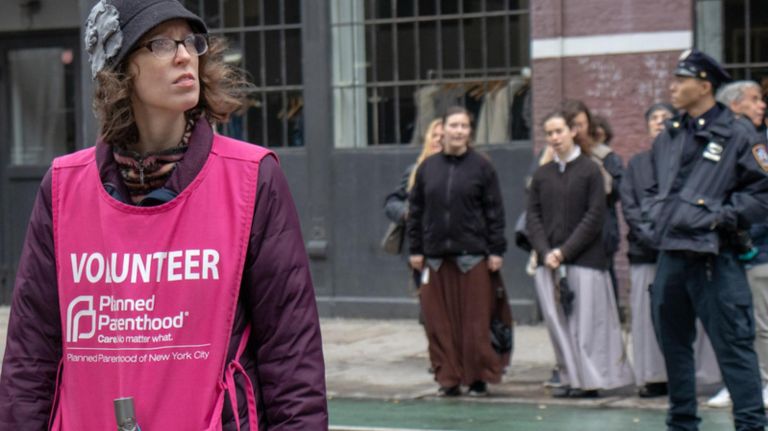 A Planned Parenthood volunteer looks for incoming patients as she keeps her back toward abortion protestors from Old Saint Patrick's Cathedral on Nov. 3, 2018.