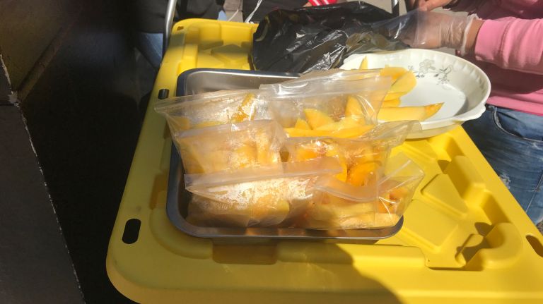 A woman sells mangoes on Seventh Avenue, hoping to escape a fine.