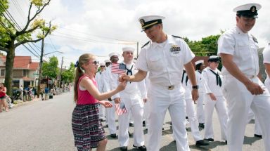 military members meeting a civilian holding an American flag during Fleet Week