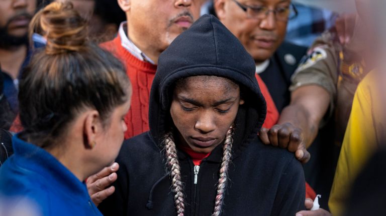 Raven Reyes, center, attends a candlelight vigil Wednesday evening in honor of her family members who died in a fire in their Harlem apartment.