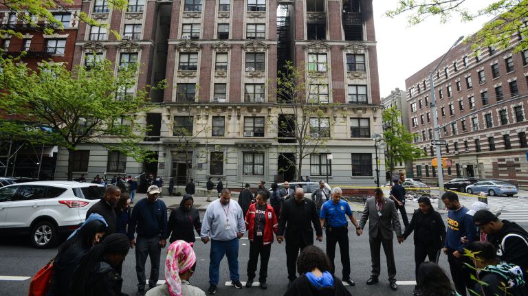 Survivors of a Harlem fire pray, along with community leaders and city officials, outside the&nbsp;building on Adam Clayton Powell Jr. Boulevard on Wednesday afternoon.