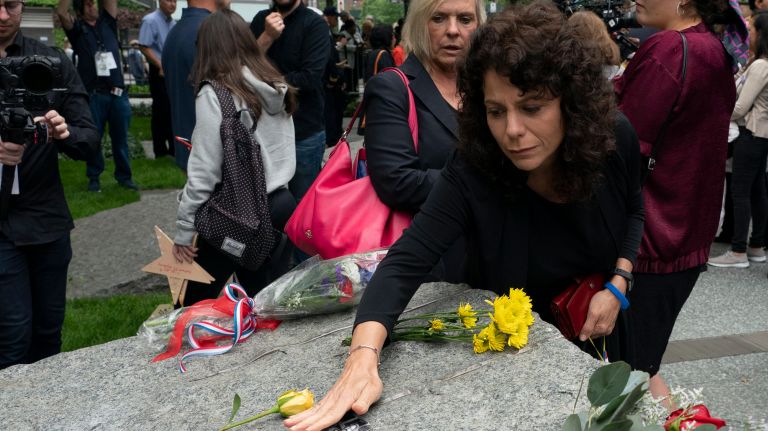 Joanna Reisman, the widow of Lt. Steven Reisman, places a photograph of her husband on one of the monoliths Thursday.